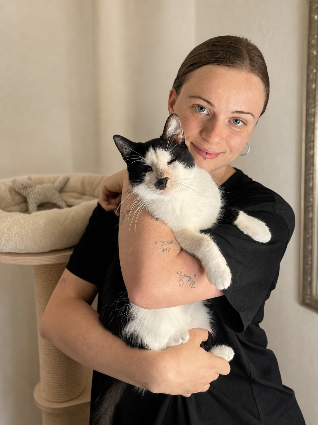 Louise Kruszelnicki hält eine schwarz-weiße Katze in einem hellen Wohnzimmer im Arm